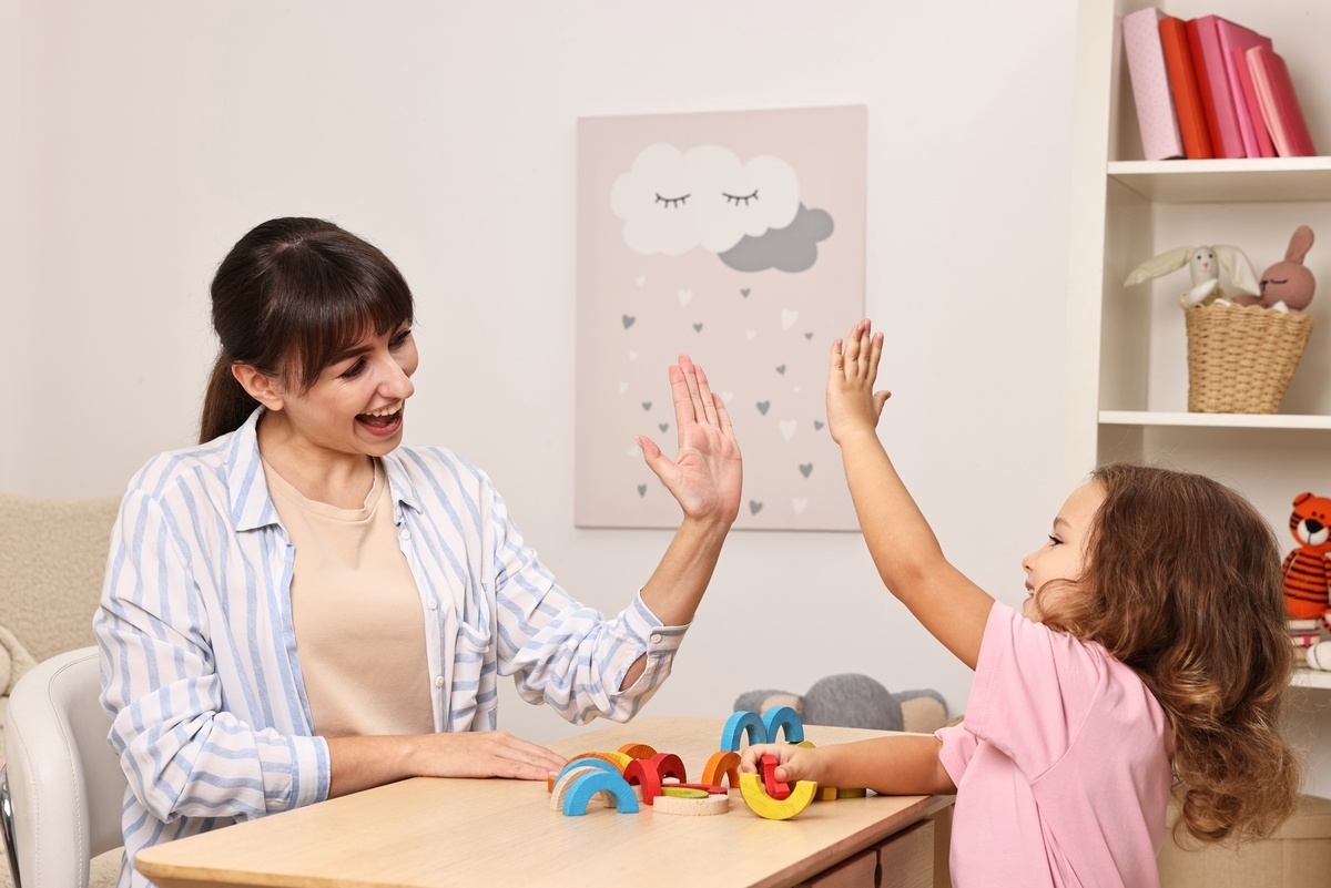 Caregiver giving a high-five to a child during autism support in the Bronx