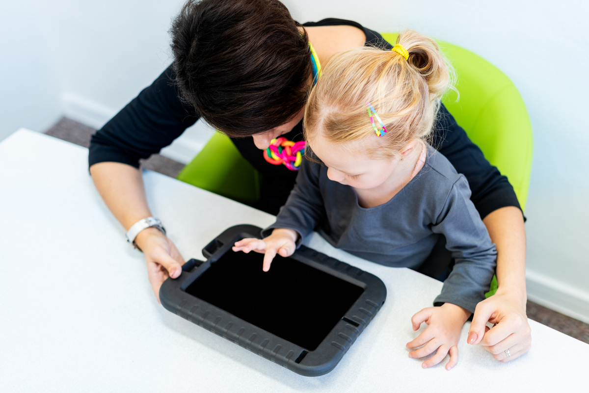 Child using an AAC device for nonverbal support in Queens