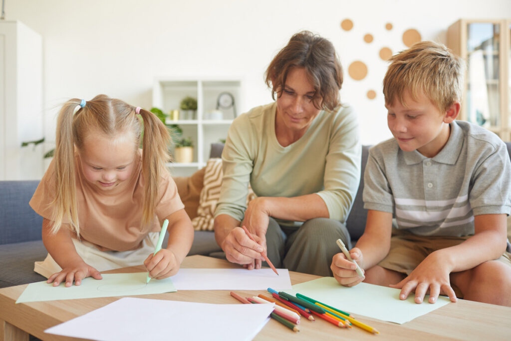 Special needs siblings drawing together with their mother at home