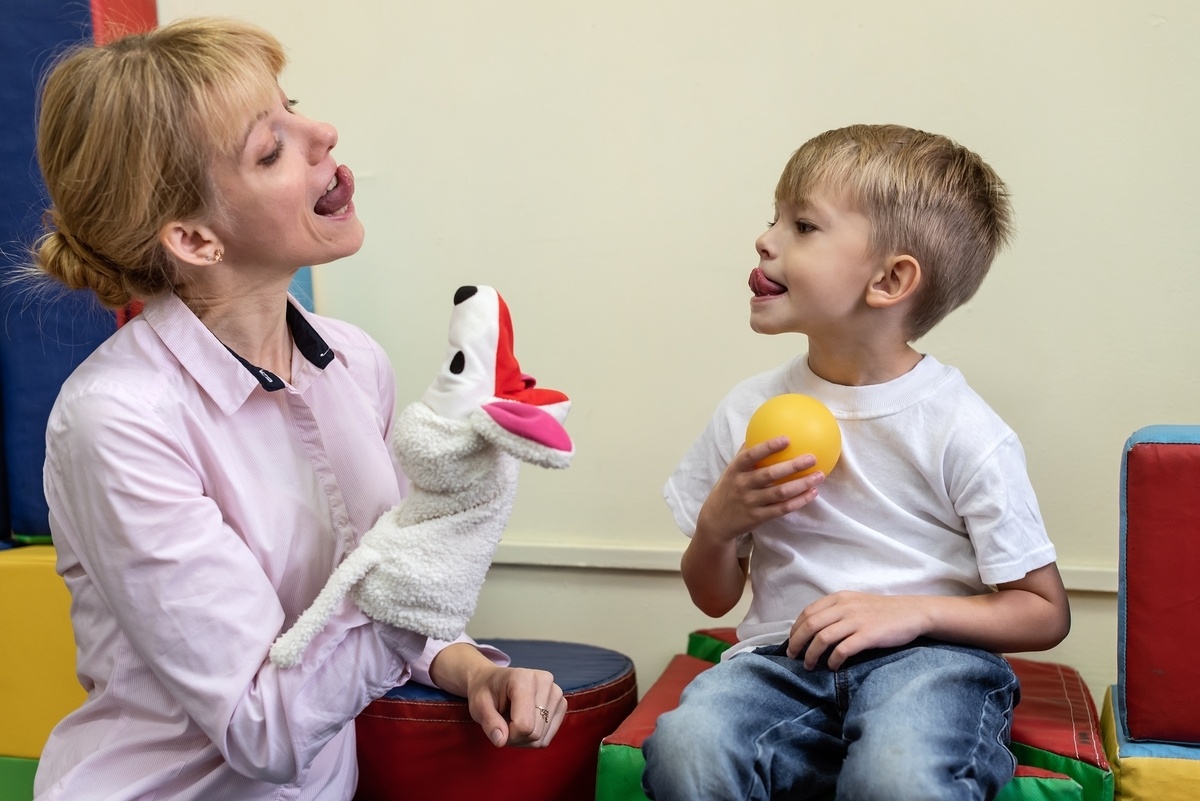 Speech therapist and child during a speech therapy evaluation testing oral motor skills