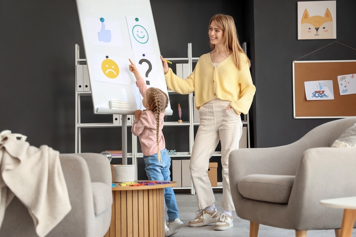 Caregiver helping a child use a picture communication board for nonverbal support in Brooklyn, NY